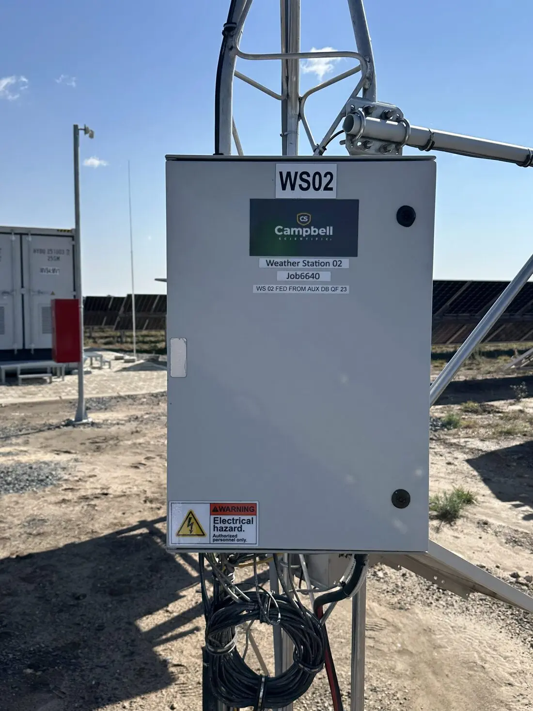 Campbell Scientific weather-station enclosure, labelled WS02, on a mast beside the solar array