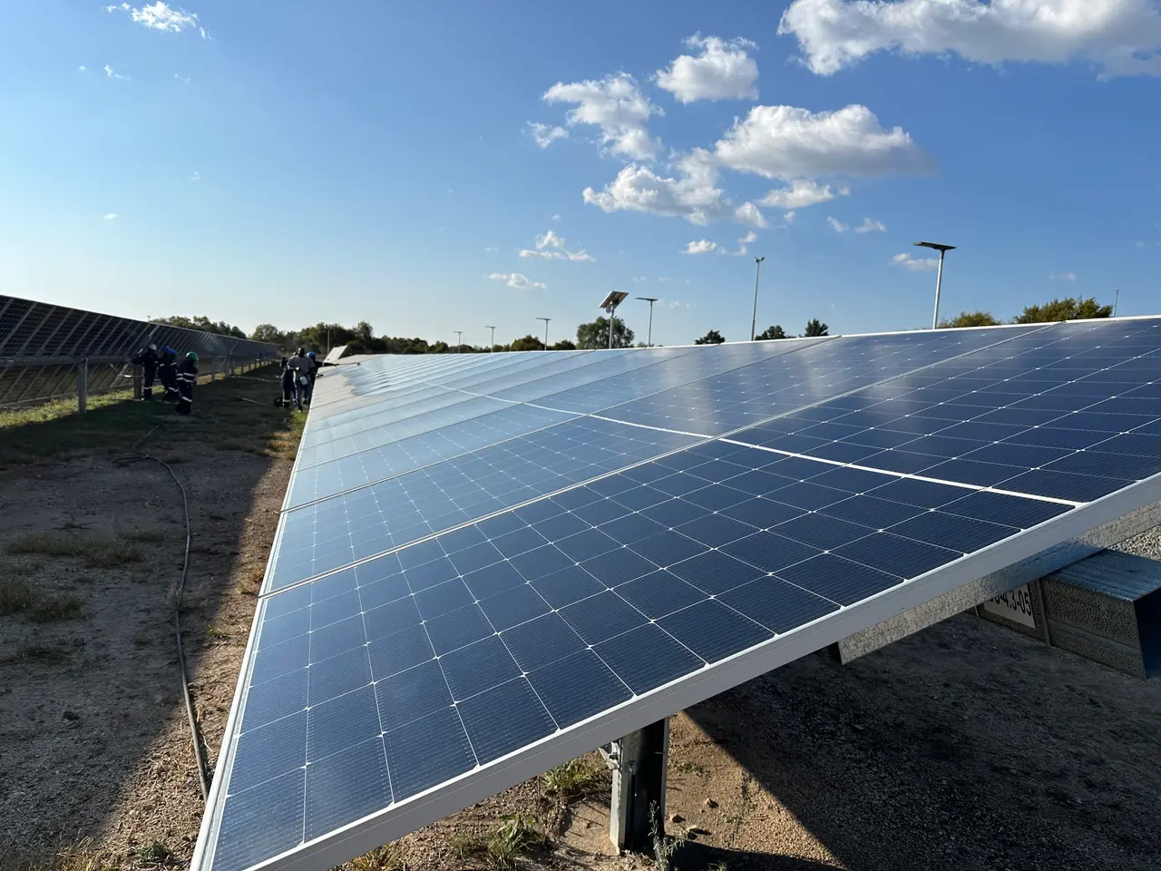Wide angled view of a clean panel row with a small cleaning crew and hose visible in the distance